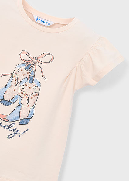 Pink t-shirt with a graphic design of feet and a bow on a light gray background