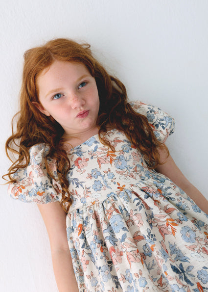 Young girl wearing a floral dress against a white background