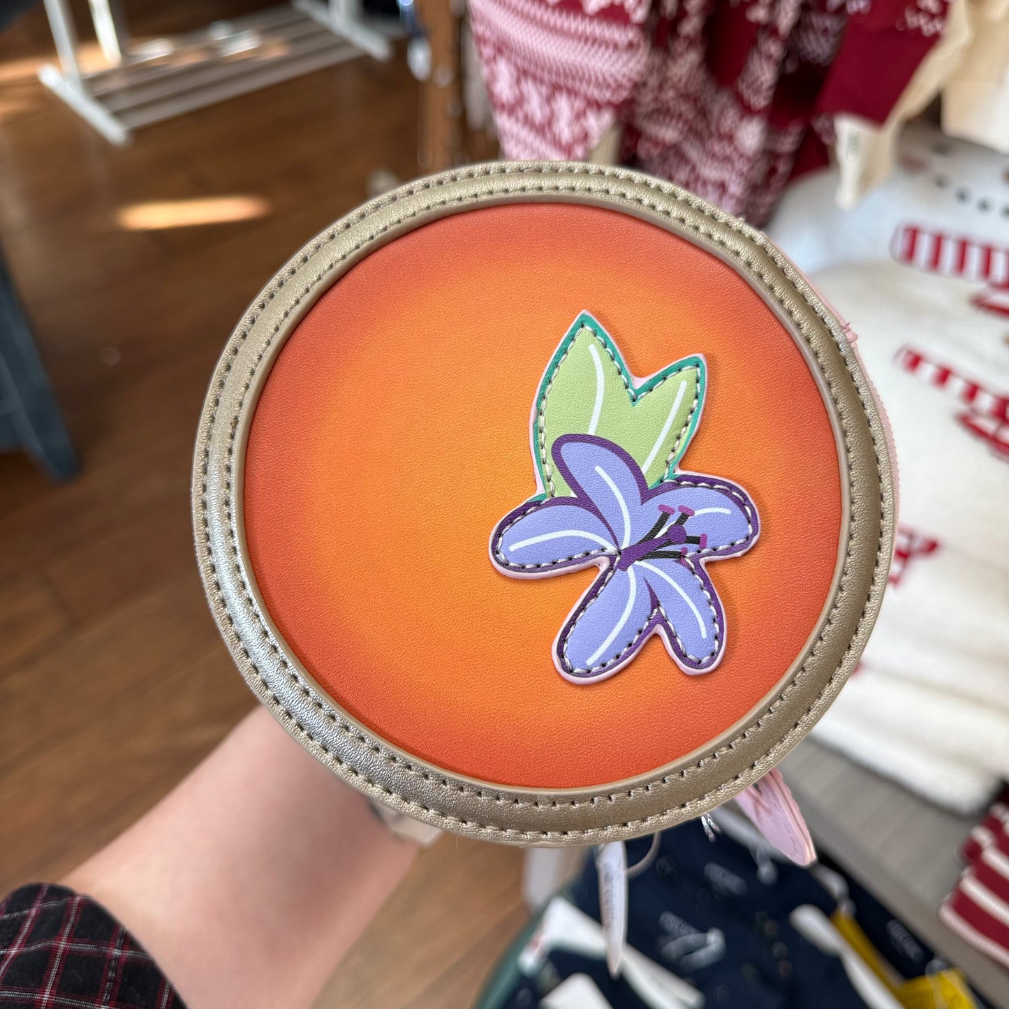 Round orange object with a purple flower design held in front of a store setting.