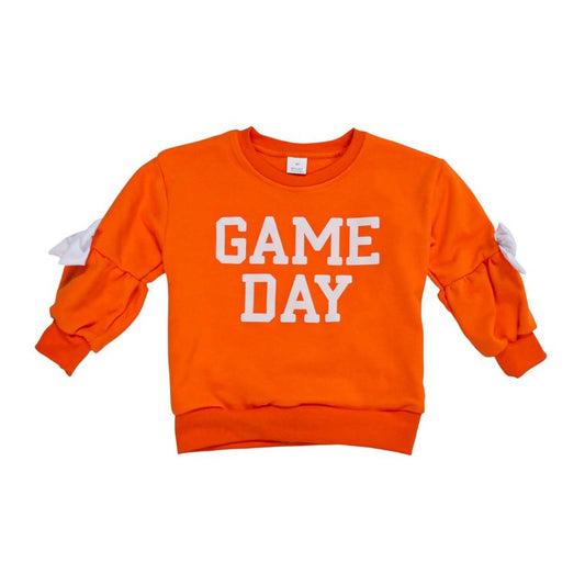 An orange crewneck sweatshirt with 'GAME DAY' printed in white block letters on the front, featuring white bow details on the sleeves, shown against a plain white background.
