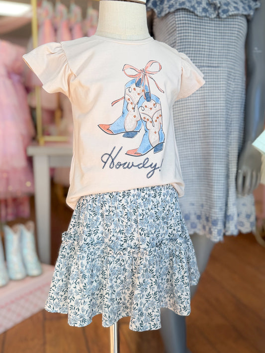 Children's outfit with a t-shirt and floral skirt on a mannequin in a store setting.