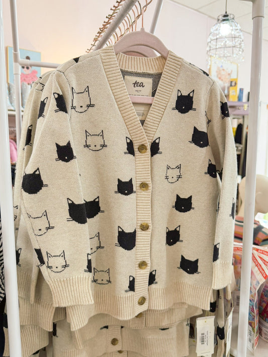 Beige cardigan with black cat pattern on a rack in a store setting