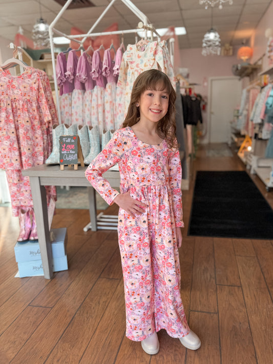 Young girl in a floral romper standing in a clothing store.