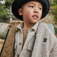Child wearing a black hat and layered clothing outdoors