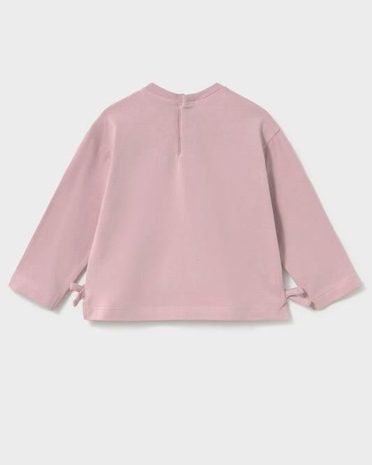 A dusty pink long-sleeve top shown from the back, featuring a simple crew neck and side tie details at the cuffs, photographed against a light gray background.