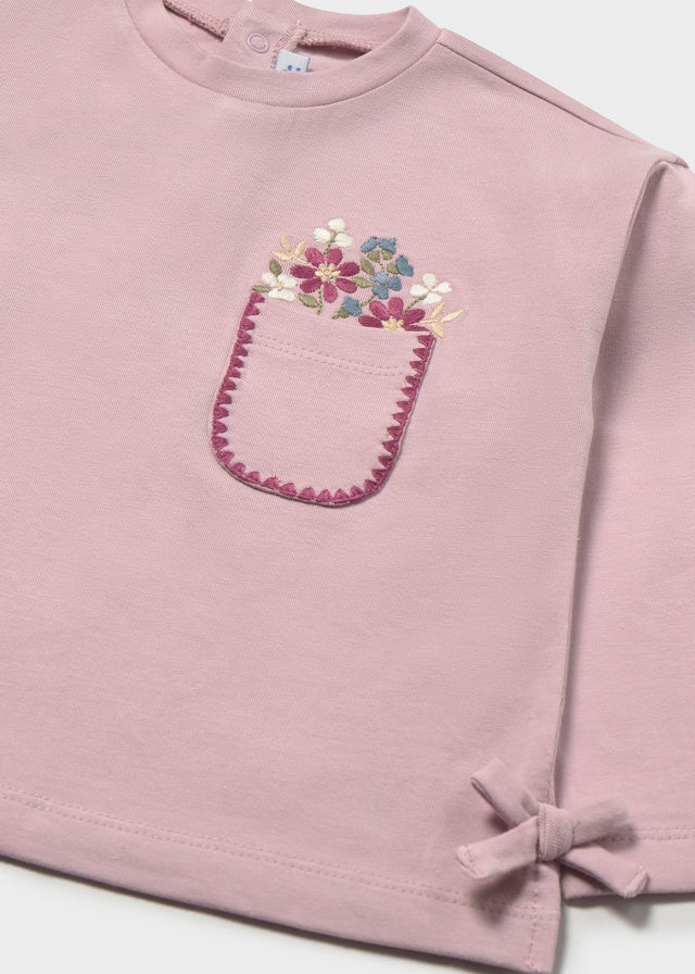 Pink t-shirt with floral pocket design on a white background
