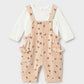 Cream corduroy overall set with white long sleeve top underneath. 