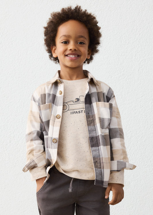 Child wearing a plaid shirt over a graphic t-shirt with a plain background