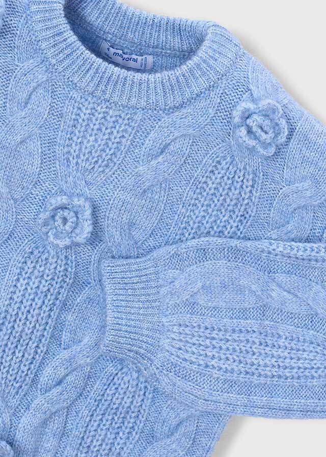 Close-up of a blue knitted sweater with floral patterns on a white background