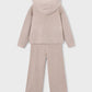 A two-piece children's knit loungewear set in a light beige color, featuring a hooded sweatshirt and matching wide-leg pants, shown from the back on a light gray background.