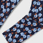 A close-up of a navy blue fabric with a repeating floral pattern in light blue and orange-brown, laid diagonally on a light gray background.