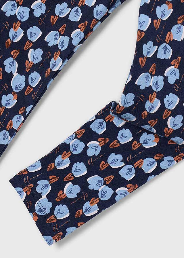 A close-up of a navy blue fabric with a repeating floral pattern in light blue and orange-brown, laid diagonally on a light gray background.