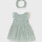 Green baby dress with ruffled details and matching headband on a light gray background