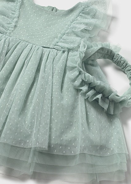 Green polka dot dress with ruffled details on a light background