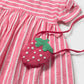 Pink and white striped dress with a strawberry-shaped purse on a white background