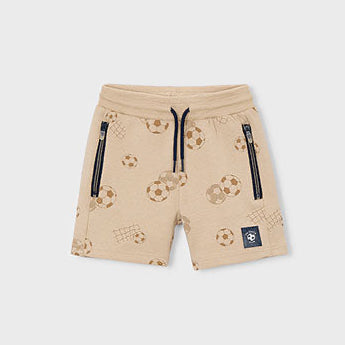 Beige shorts with soccer ball pattern on a tan background
