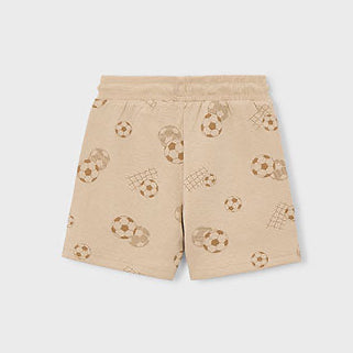 Beige shorts with soccer ball pattern on a tan background