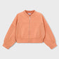 Peach-colored jacket with quilted sleeves on a light gray background