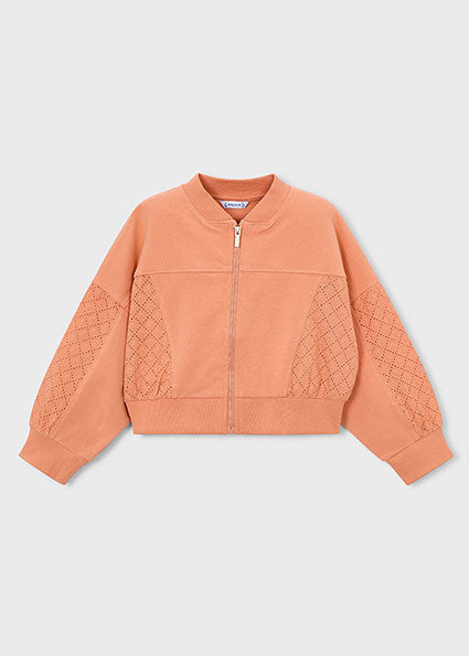 Peach-colored jacket with quilted sleeves on a light gray background