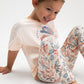 Child wearing a white shirt with a colorful design and floral leggings on a light background
