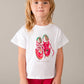 Child wearing a white t-shirt with red shoes and 'Dolce Vita' text on a plain background