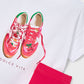 White t-shirt with red sneakers graphic, pink pants, and 'Dolce Vita' branding on a white background.