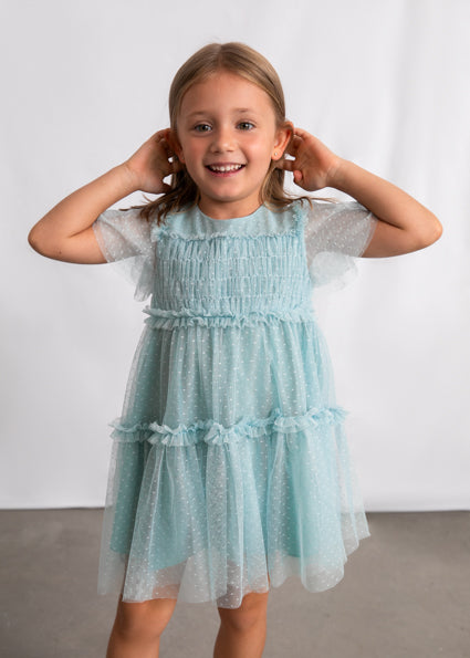 Young girl wearing a light blue dress against a white background