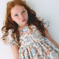 Young girl wearing a floral dress against a white background