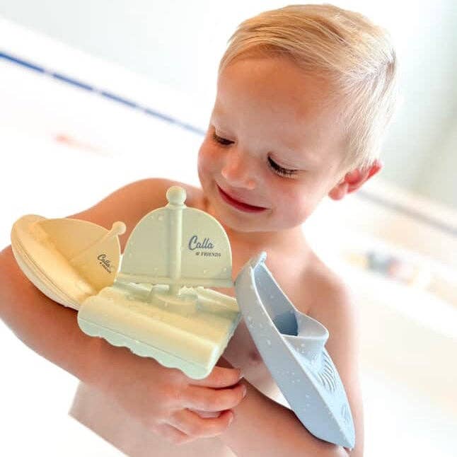 Child holding a set of bath toys including a boat and a castle, with 'Culla' branding.