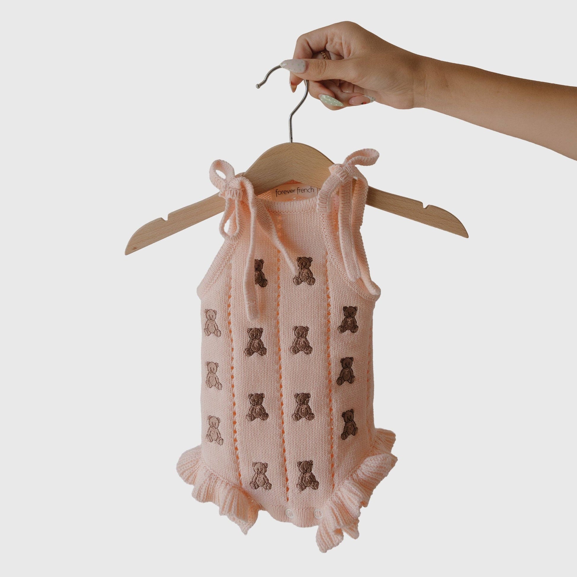 Baby romper with bear pattern on a hanger against a white background
