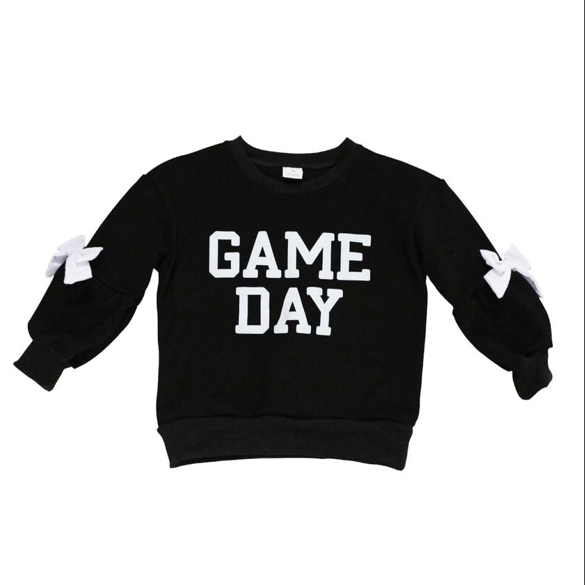 A black long-sleeve sweatshirt with 'GAME DAY' printed in bold white block letters across the chest, featuring white bow details on the sleeves, shown against a plain white background.