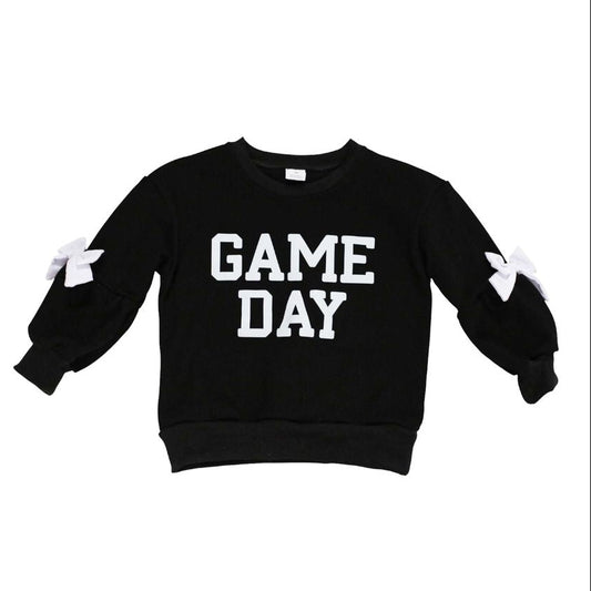 A black long-sleeve sweatshirt with 'GAME DAY' printed in bold white block letters across the chest, featuring white bow details on the sleeves, shown against a plain white background.