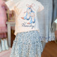 Children's outfit with a t-shirt and floral skirt on a mannequin in a store setting.