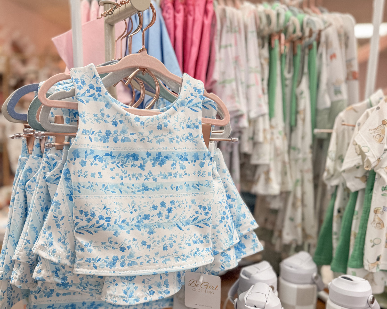 blue and white floral set hanging on a tabletop rack, other clothes in the background in a shop setting. 