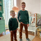 Two children standing in a room with a neutral background