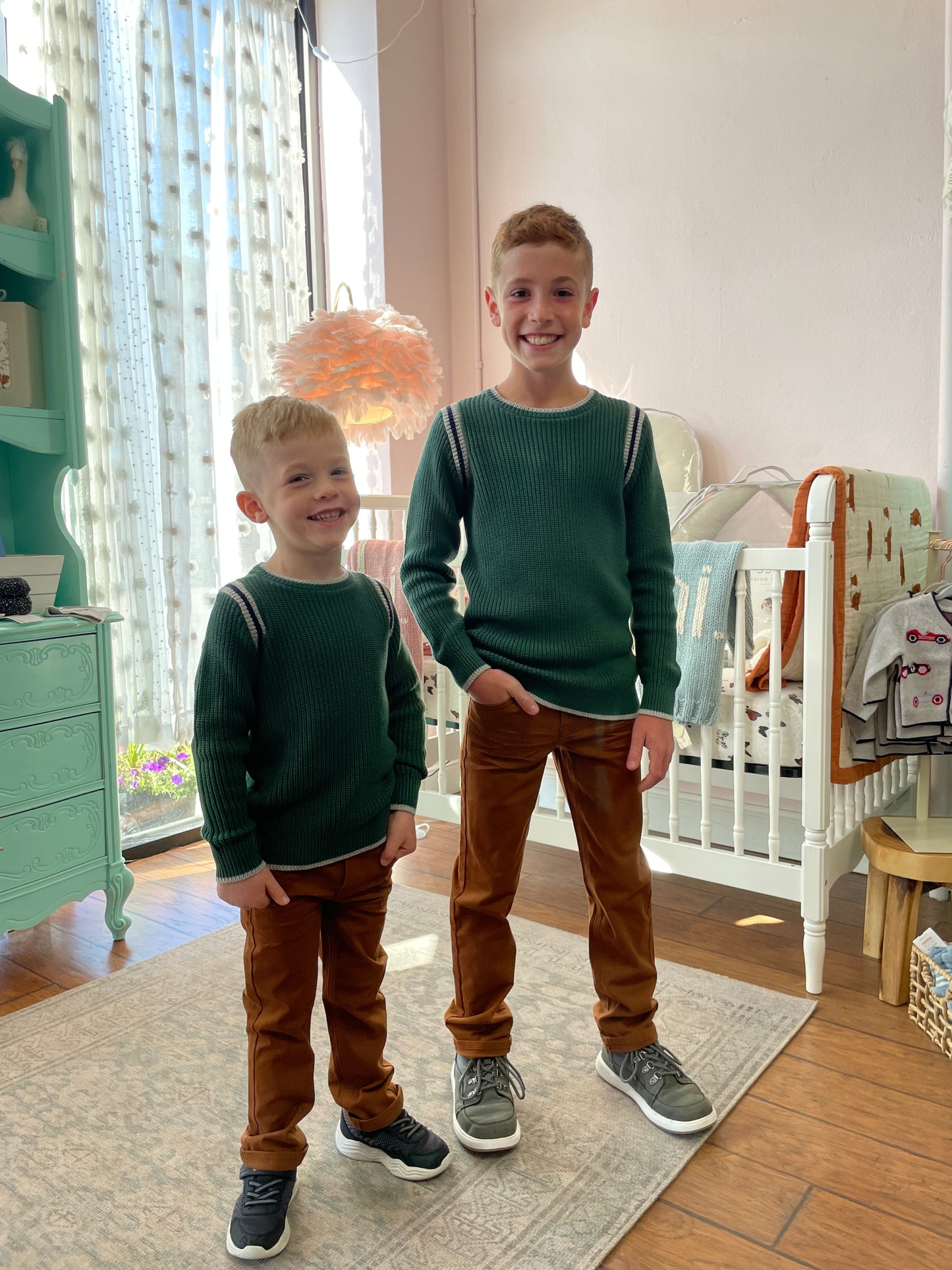 Two children standing in a room with a neutral background