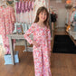 Young girl in a floral romper standing in a clothing store.