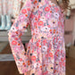 Person wearing a floral romper with a blurred indoor background
