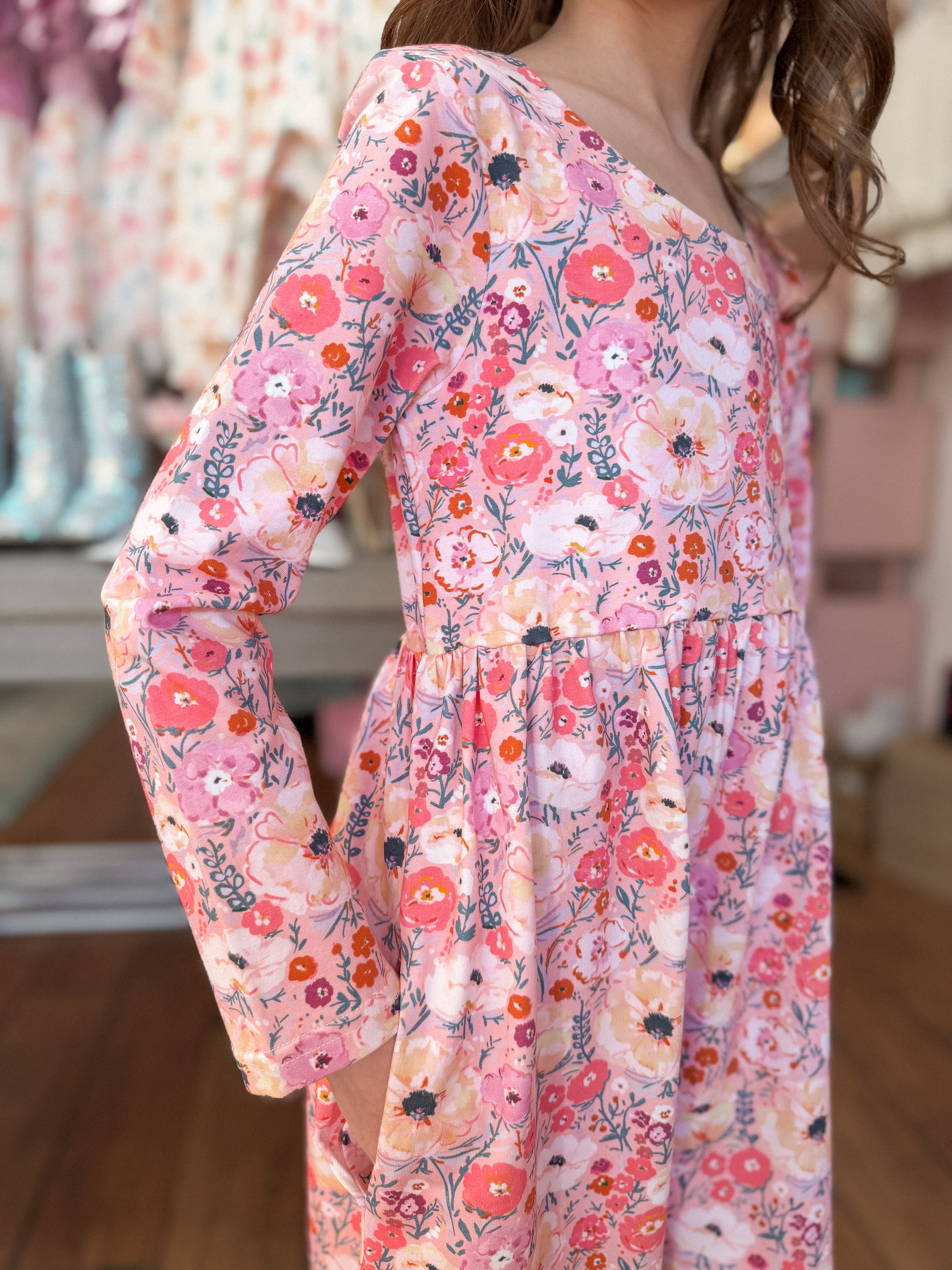 Person wearing a floral romper with a blurred indoor background