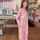 Young girl in a floral romper standing in a store with clothing and shoes in the background.
