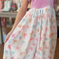 Person wearing a dress with purplish pink top and patterned skirt in a store setting