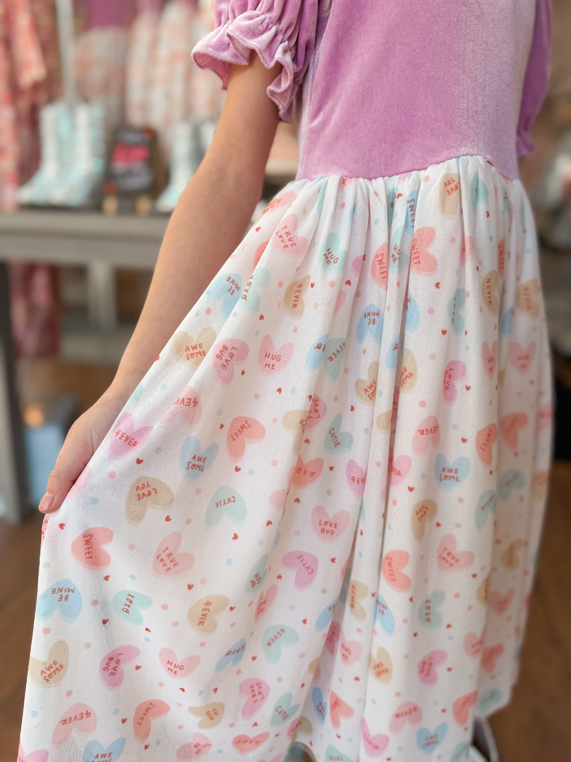 Person wearing a dress with purplish pink top and patterned skirt in a store setting