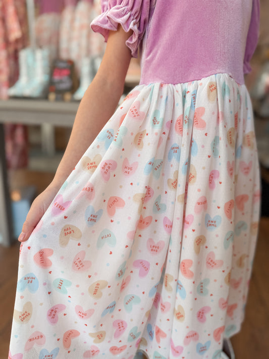 Person wearing a dress with purplish pink top and patterned skirt in a store setting