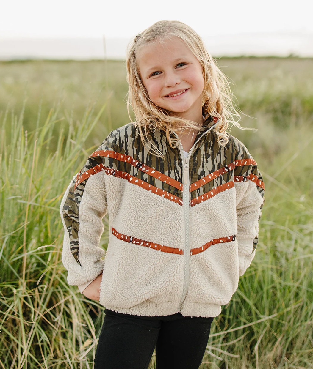 Child wearing a camouflage jacket with a white background