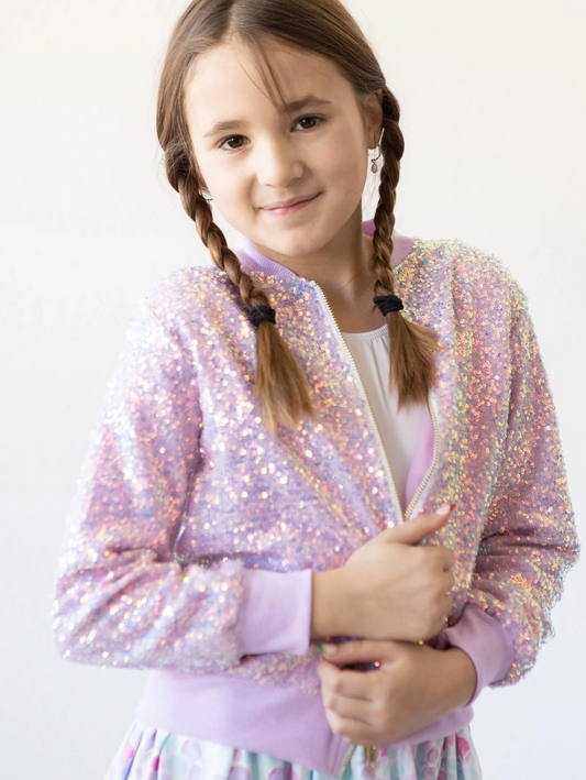 Young girl wearing a sparkly pink jacket on a white background