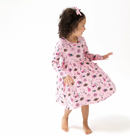 Child wearing a pink dress with football themed print on a white background