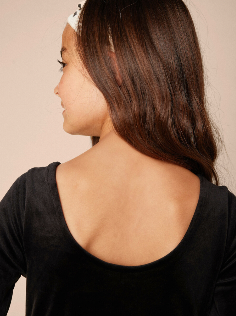 Woman wearing a black top with a plain background