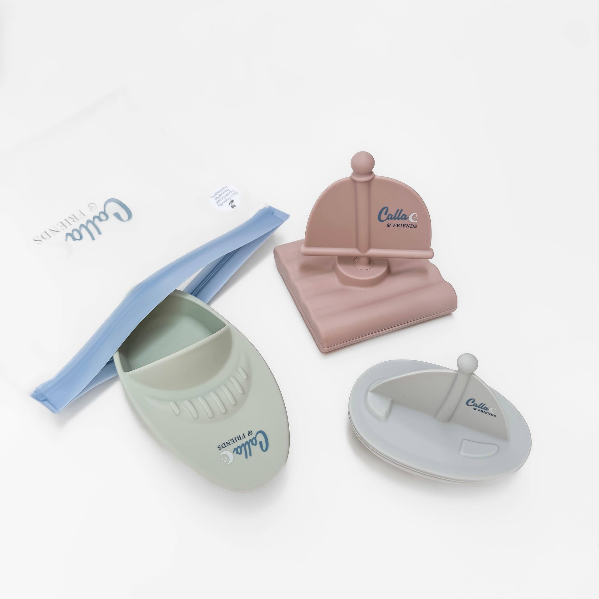 Set of baby accessories including a pink head support, blue bib, and two green and gray containers on a white background.