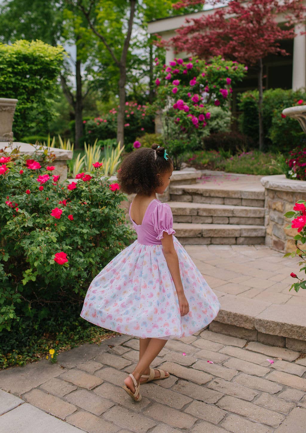 Young girl in a garden with pink flowers and stone steps