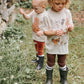 Two children in a garden wearing matching outfits with animal prints.